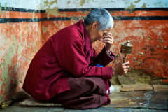 Nonne mit Gebetsmühle versunken im Gebet in Bhutan