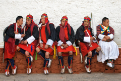 Traditionelle Soldaten sitzen in einer Reihe im Dzong von Punakha
